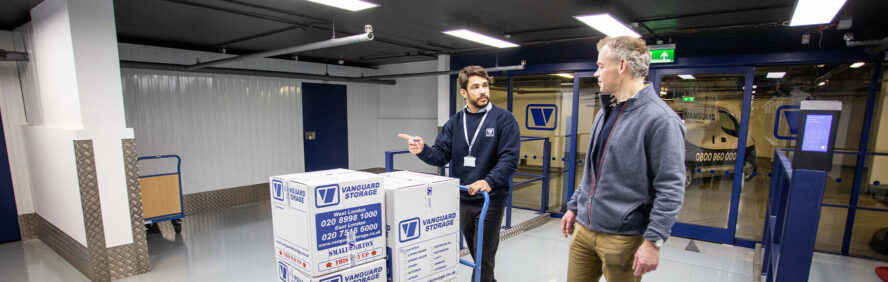 A photo showing a Vanguard employee helping a customer take Vanguard boxes into a storage unit.
